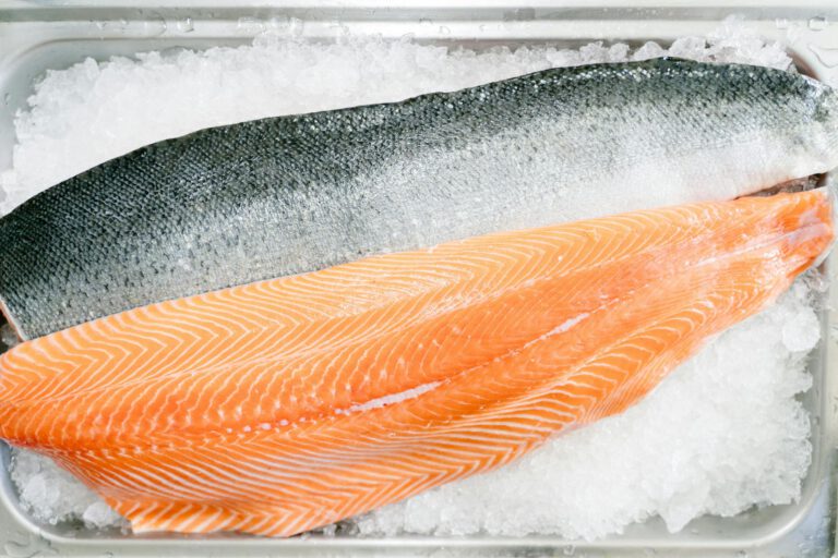 Close-up of a raw salmon fillet on ice, showcasing its fresh and high-quality texture.